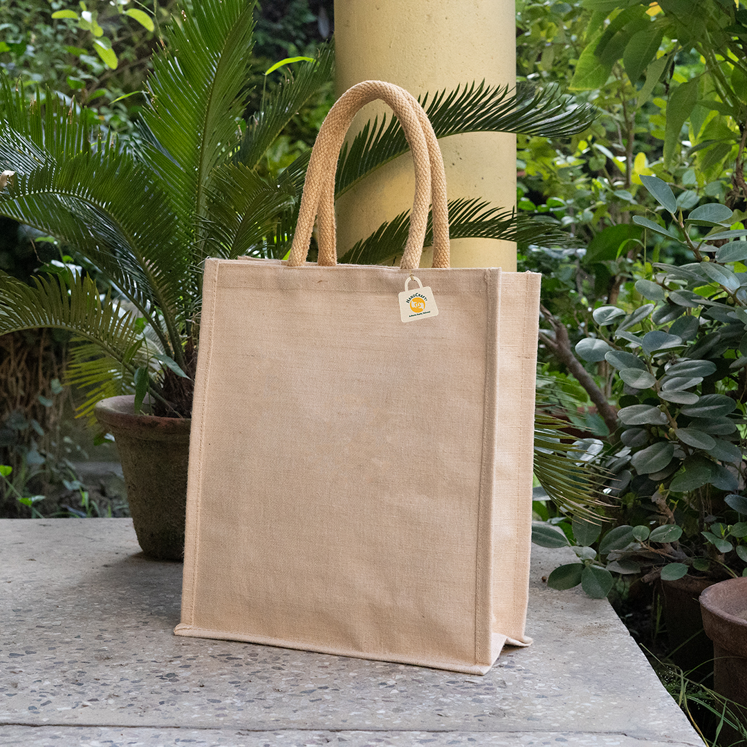 Plain natural-colour bag with padded jute handles and side gussets, standing on a stone ledge